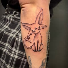 Zwart-wit Espeon Pokémon tattoo op de bovenarm.