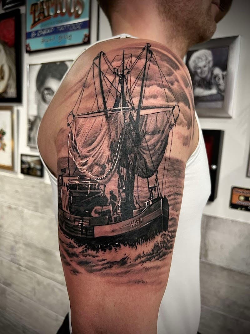 Realistische zwart-wit tattoo van een vissersboot op zee op de bovenarm.