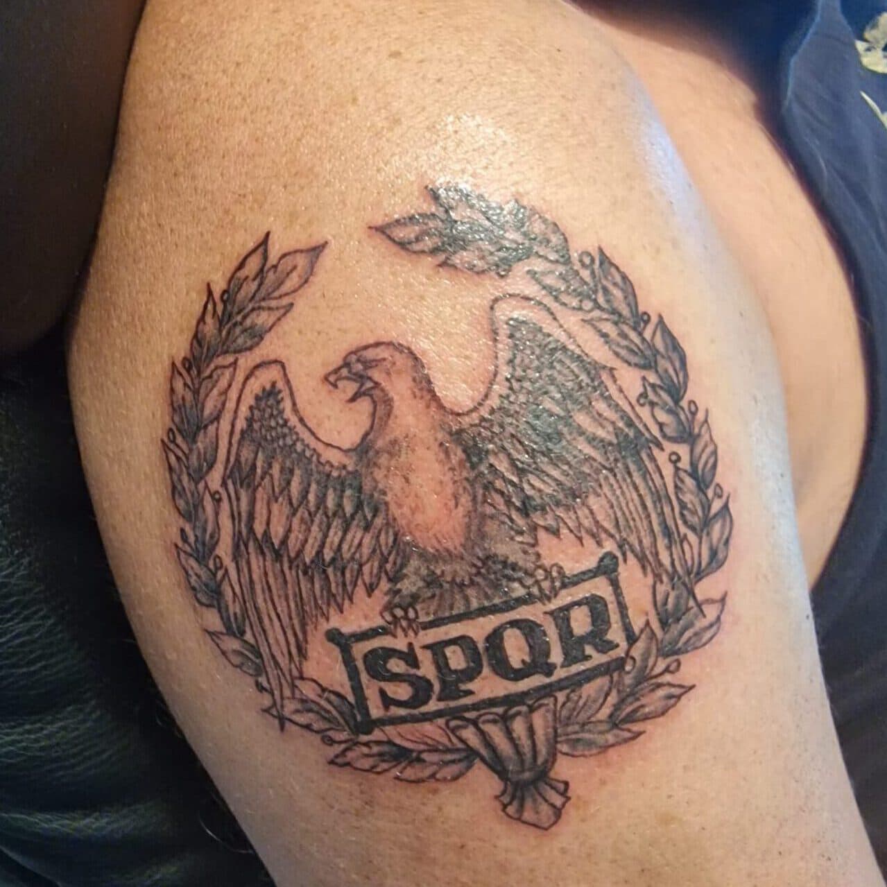 Zwart-wit tattoo van een Romeinse adelaar met lauwerkrans en SPQR banner.