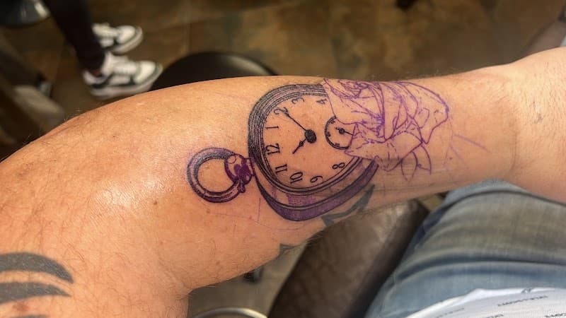 Zakhorloge tattoo met roos stencil op onderarm.