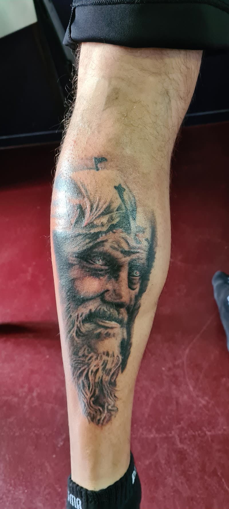 Realistisch zwart-wit portret van een bebaarde man, mogelijk Jezus, op het onderbeen.