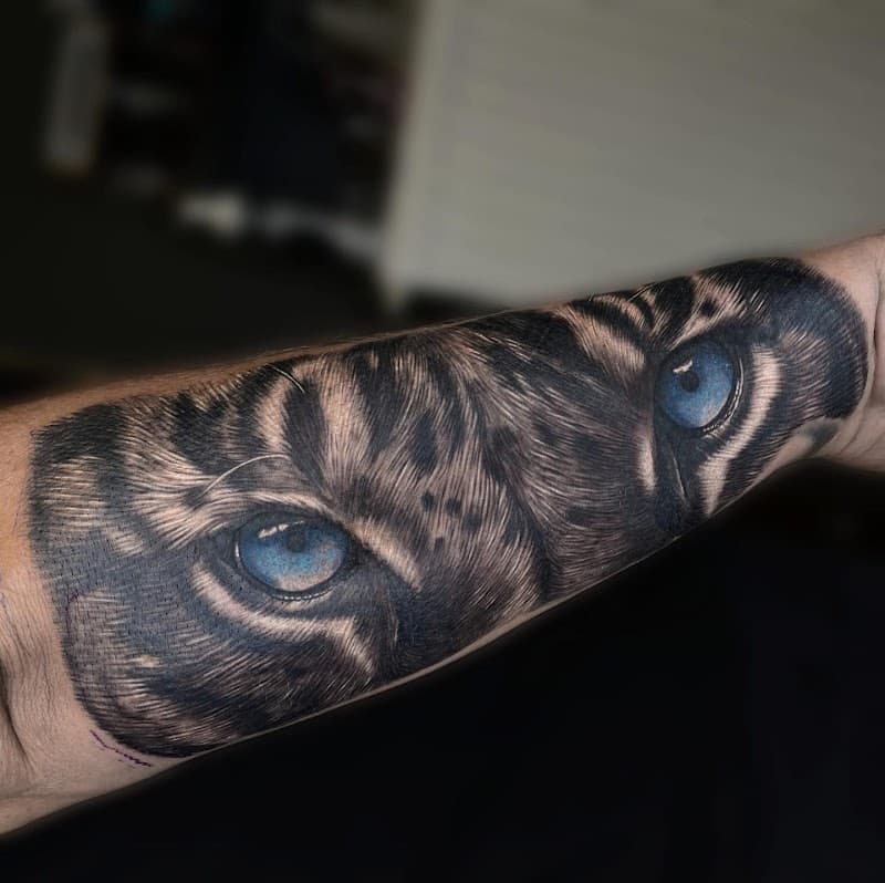 Realistische tijgerogen met blauwe irissen op de onderarm.