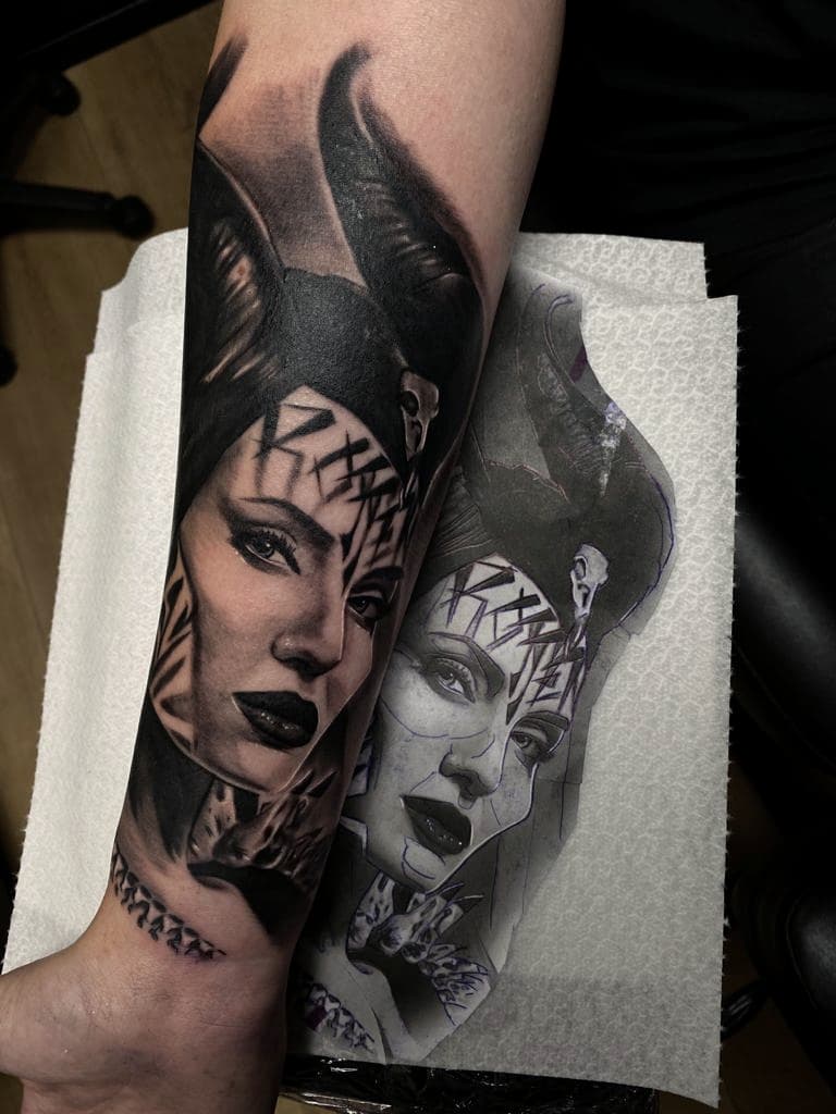 Zwart-wit portret van Maleficent met hoorns en gezichtsmarkeringen op onderarm.