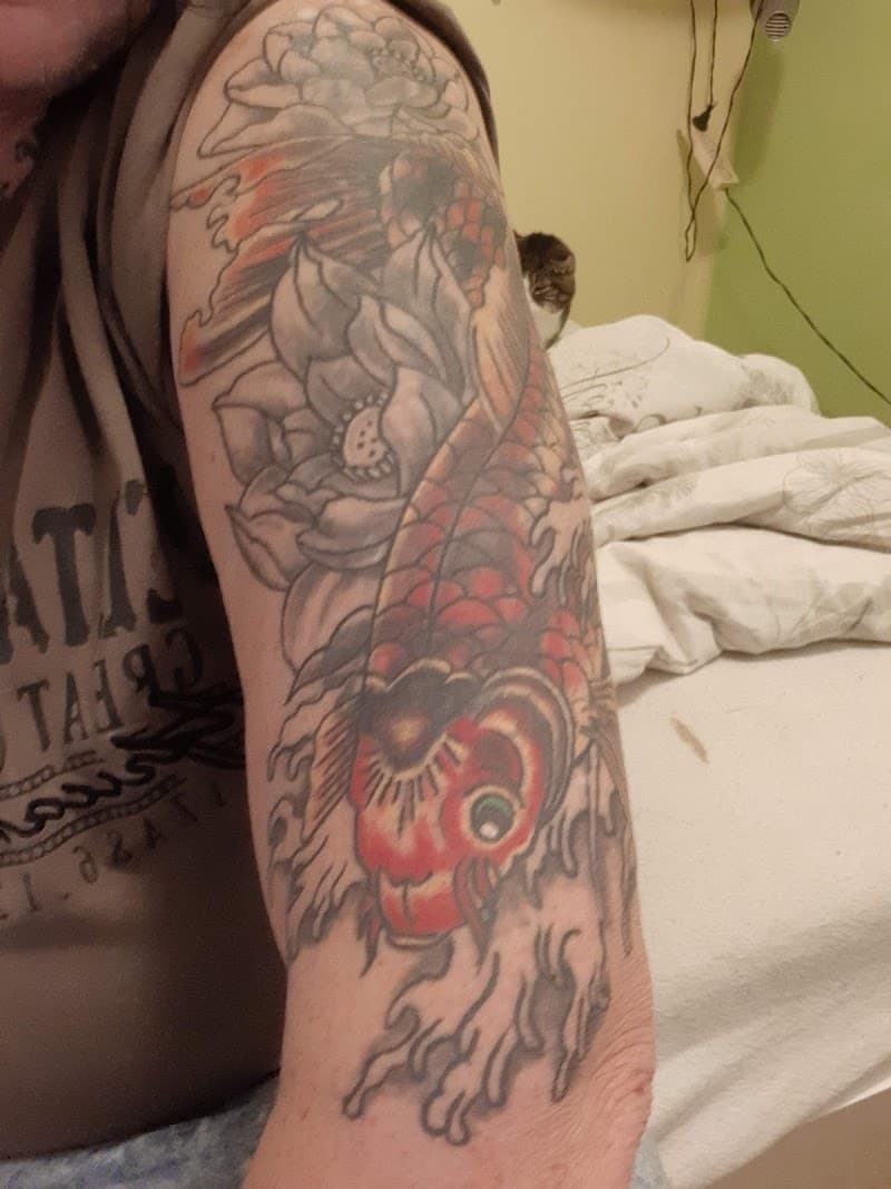 Japanse koi karper en lotusbloemen op bovenarm.