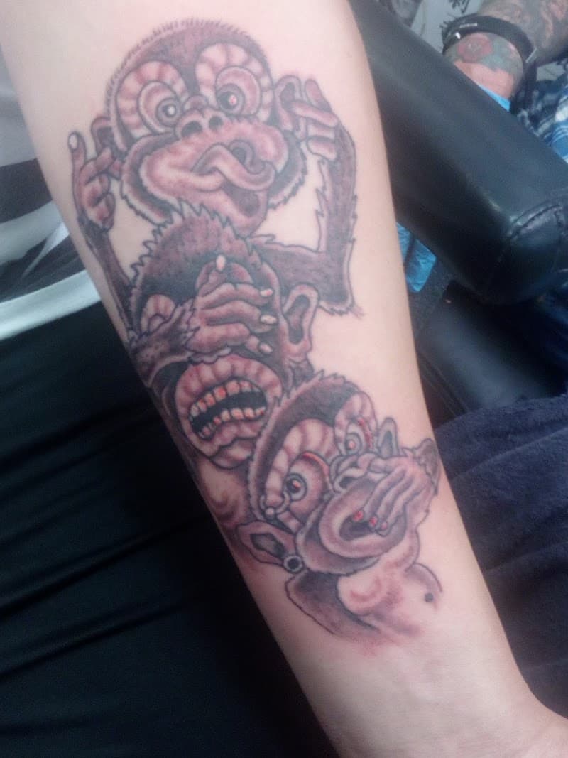Illustratieve tattoo van de drie wijze apen (horen, zien, zwijgen) op de onderarm.