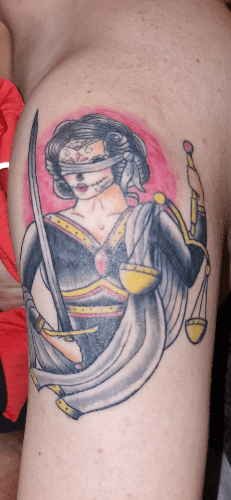 Vrouwe Justitia met suikerschedel masker en blinddoek op bovenarm.