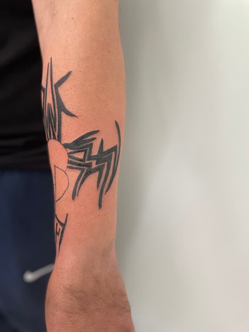 Zwarte tribal tattoo met scherpe lijnen op de onderarm.