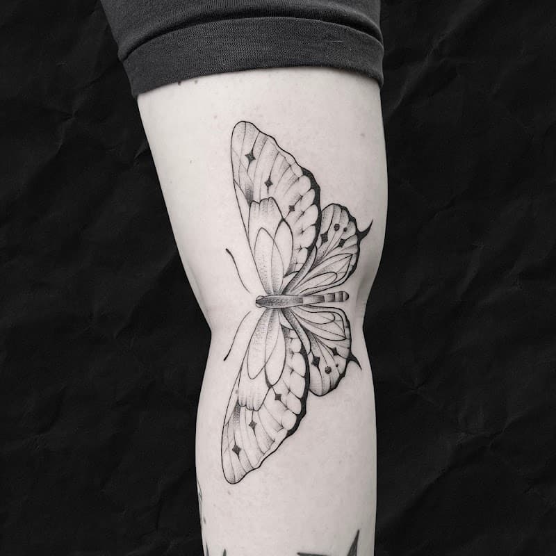 Grote vlinder tattoo met sterren op de kuit.