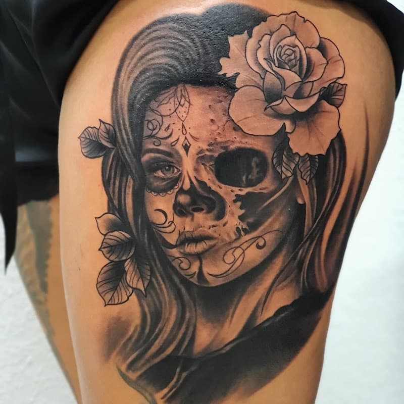 Black & grey tattoo van een vrouw met half schedelgezicht en een roos.