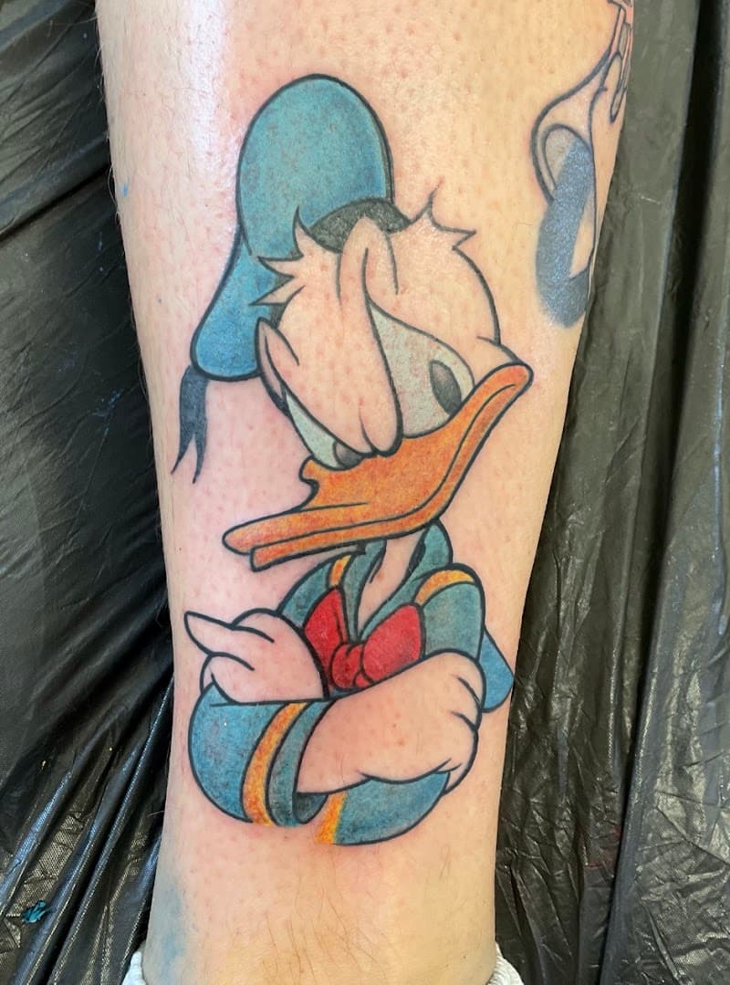 Kleurrijke Donald Duck tattoo met gekruiste armen op onderbeen.