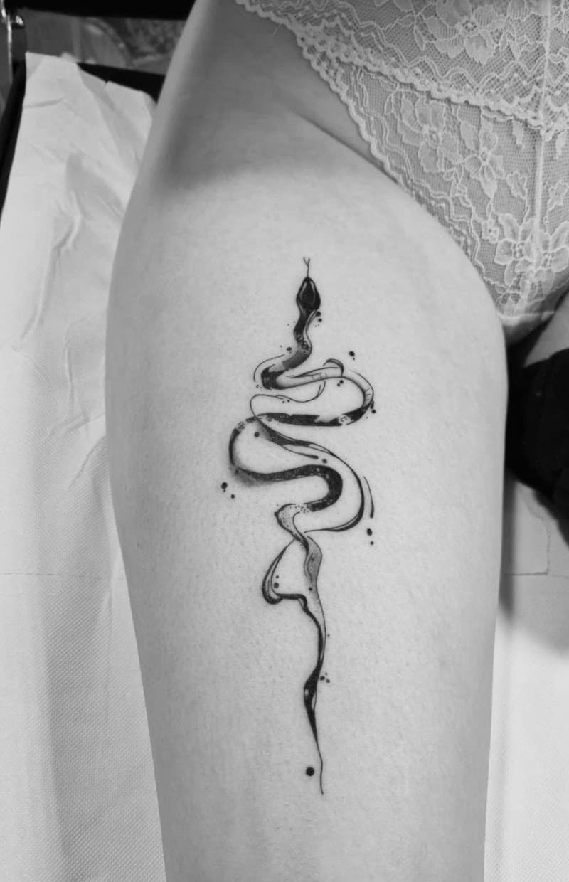 Elegante, abstracte slang tattoo op bovenbeen in zwart-wit.