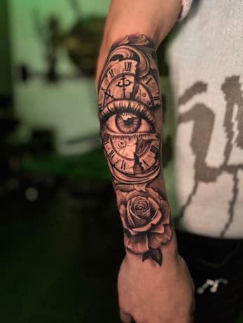 Realistisch oog in een gebroken klok met een roos eronder op de onderarm.