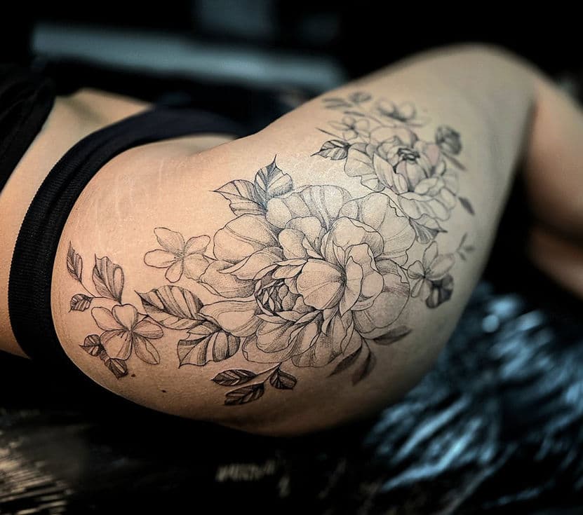 Grote fineline bloemen tattoo op heup en bovenbeen.