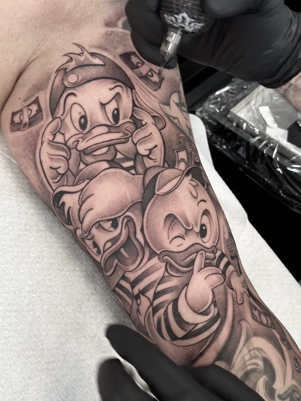 Zwart-wit tattoo van Kwik, Kwek en Kwak als Zware Jongens op een bovenarm.