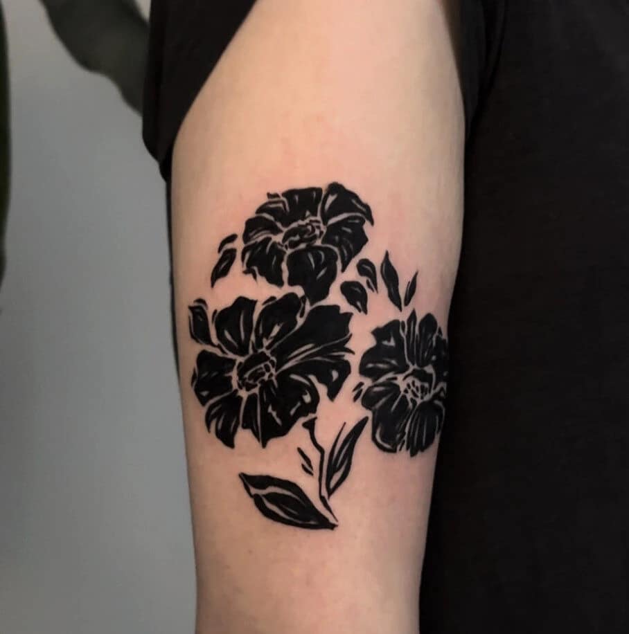 Zwarte silhouet bloemen tattoo op bovenarm.