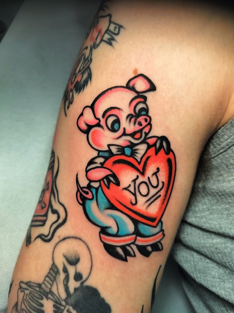 Traditional tattoo van een varkentje dat een hart met 'YOU' vasthoudt.