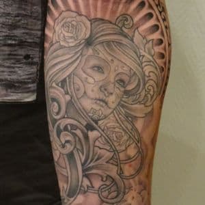 Zwart-grijze tattoo van vrouw met Day of the Dead make-up, rozen en filigraan.