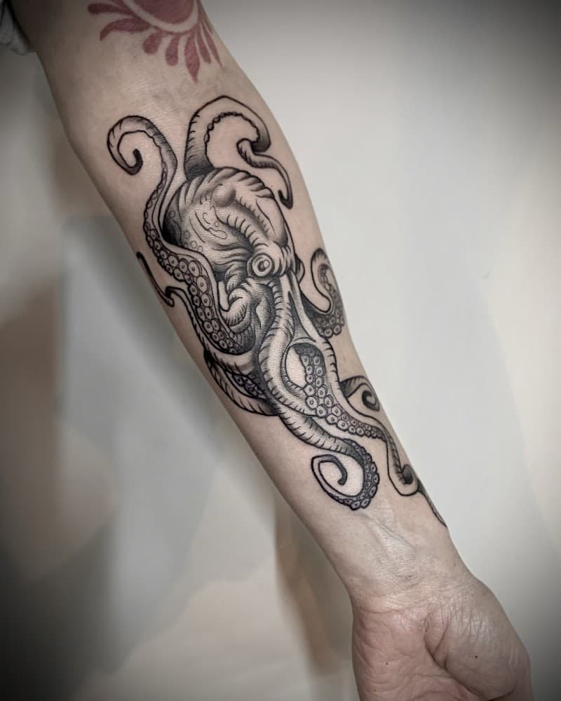 Gedetailleerde zwart-wit octopus tattoo op de onderarm.