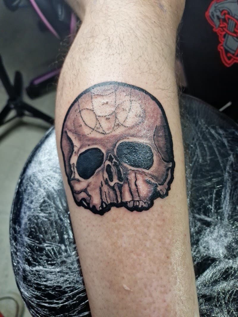 Blackwork schedel tattoo met geometrisch stippenpatroon op het voorhoofd.