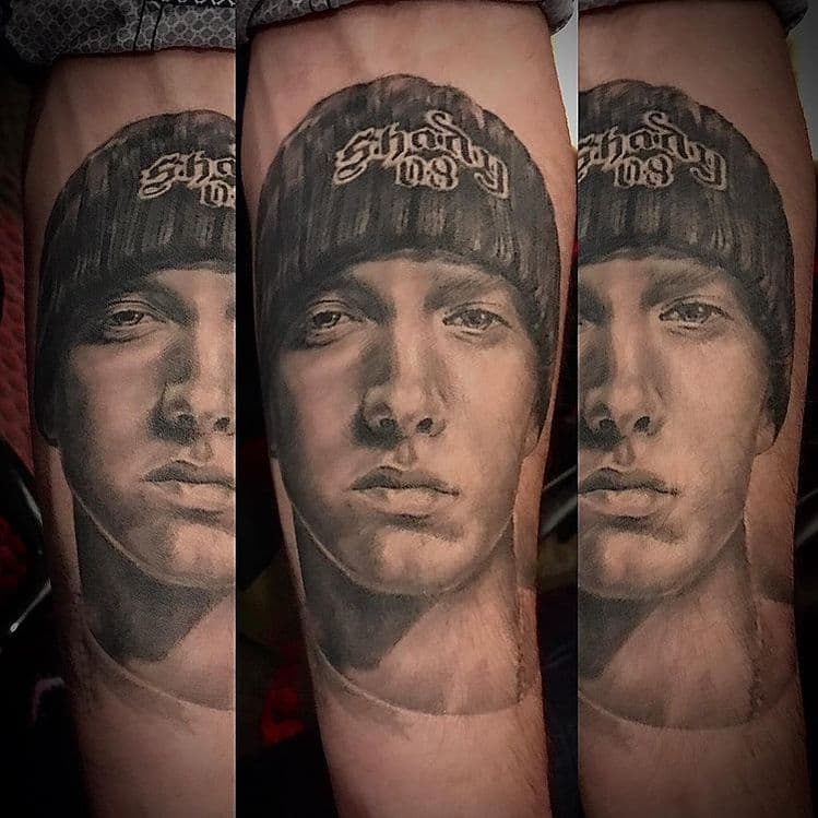 Realistisch portret van Eminem met muts op onderarm.