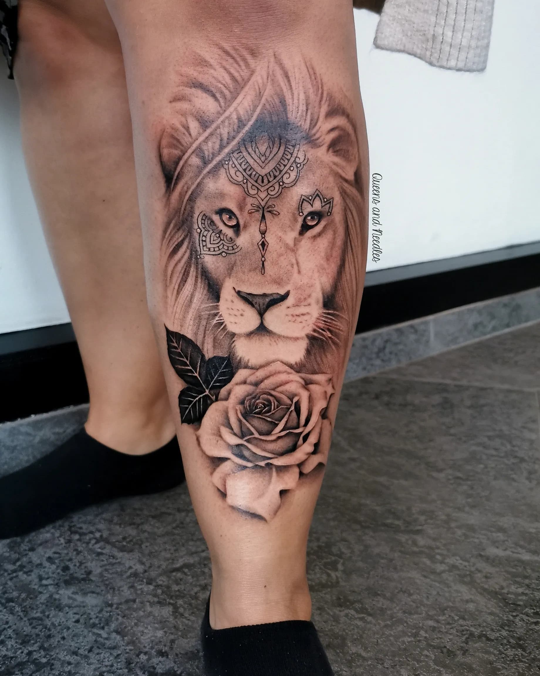 Realistische leeuw met mandala en roos op onderbeen.