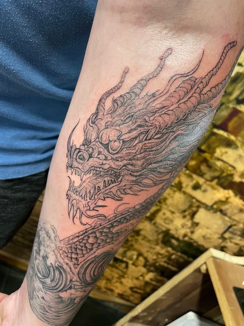 Zwart-grijze Japanse draak tattoo op onderarm.