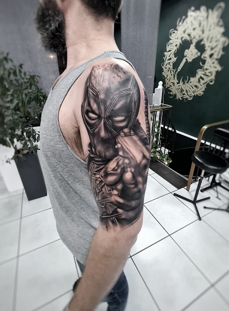 Realistische black and grey Deadpool tattoo op bovenarm.