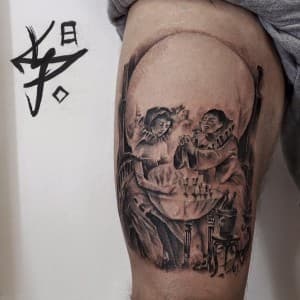 Realistische tattoo van twee figuren aan tafel die een schedel vormen.