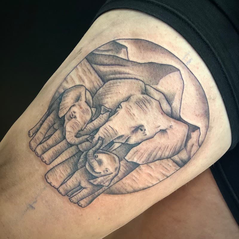 Blackwork tattoo van een olifantenfamilie in een cirkel op het bovenbeen.