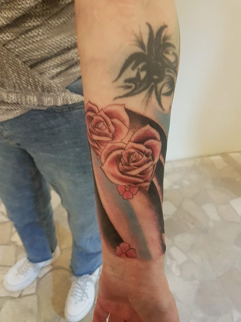 Twee roze rozen met kleine bloemetjes en een tribal ontwerp op de onderarm.