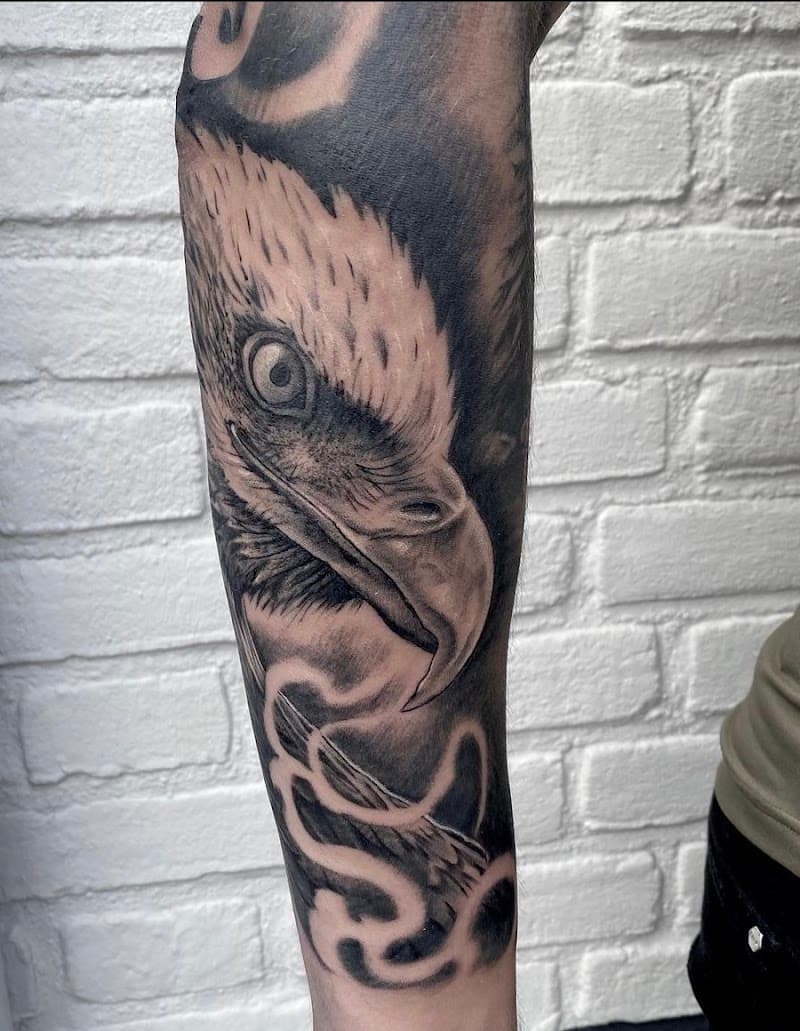 Realistische zwart-wit tattoo van een adelaarskop op de onderarm.
