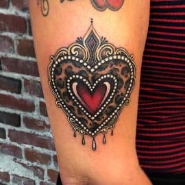 Neo-traditional hart met luipaardprint en sierlijke omlijsting op bovenarm.