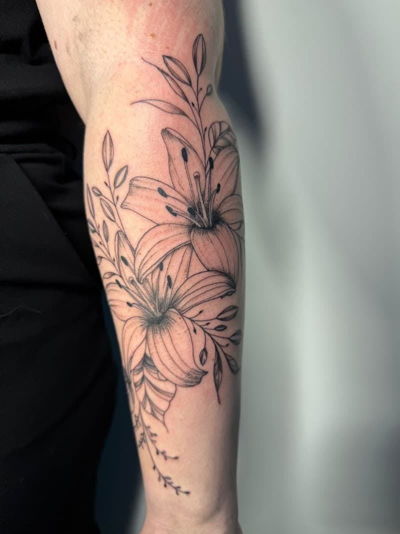 Fineline tattoo van twee lelies met bladeren op de onderarm.