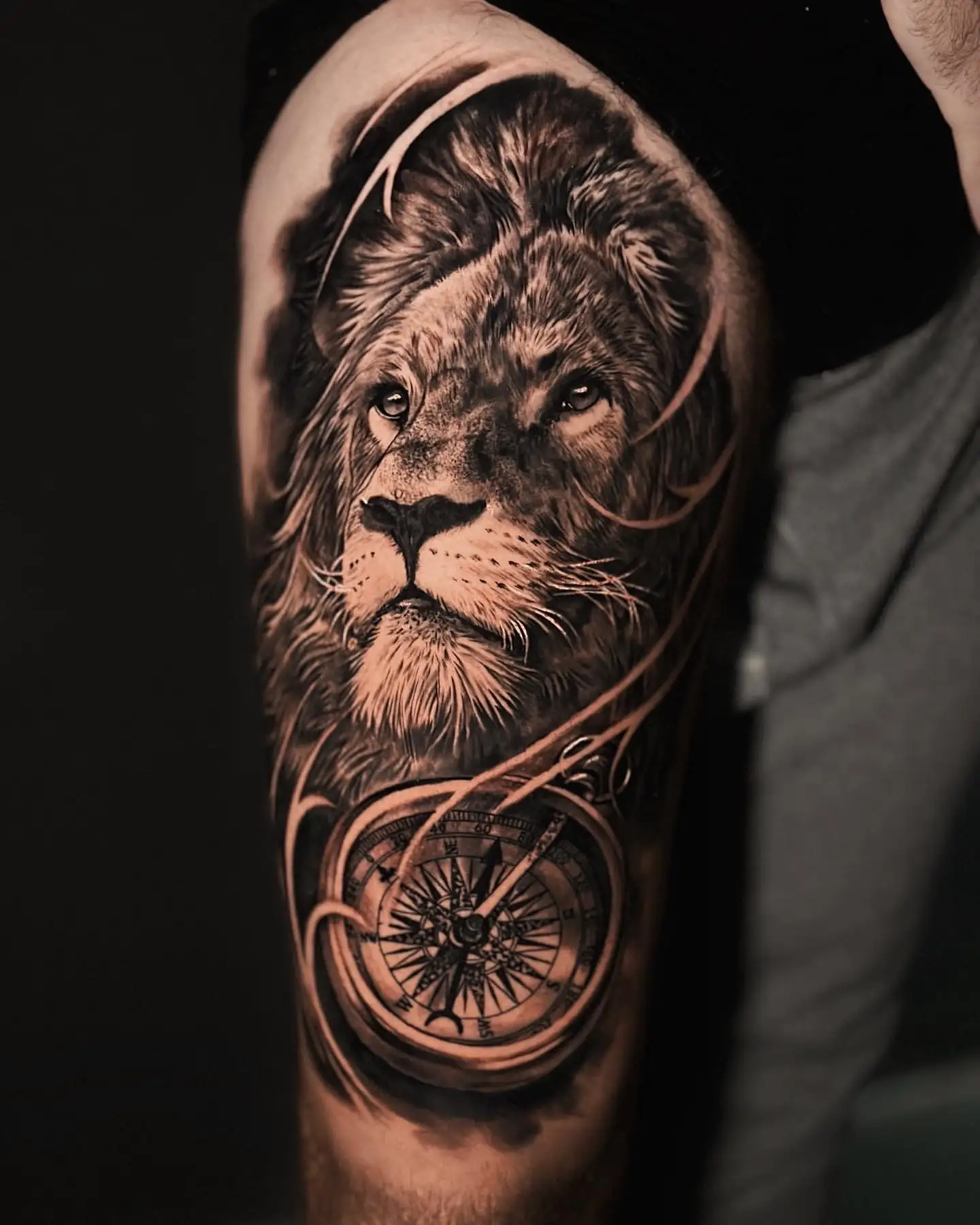 Realistische leeuw en kompas tattoo op bovenbeen.
