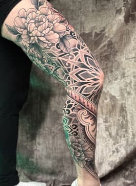 Grote mandala en bloemen been-sleeve tattoo.