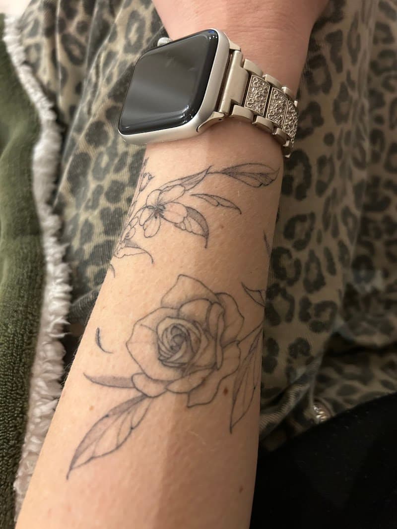 Fineline roos en bloementak op onderarm.