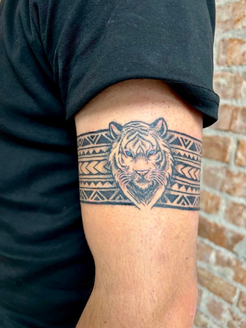 Tribal armband tattoo met een tijgerkop op de bovenarm.