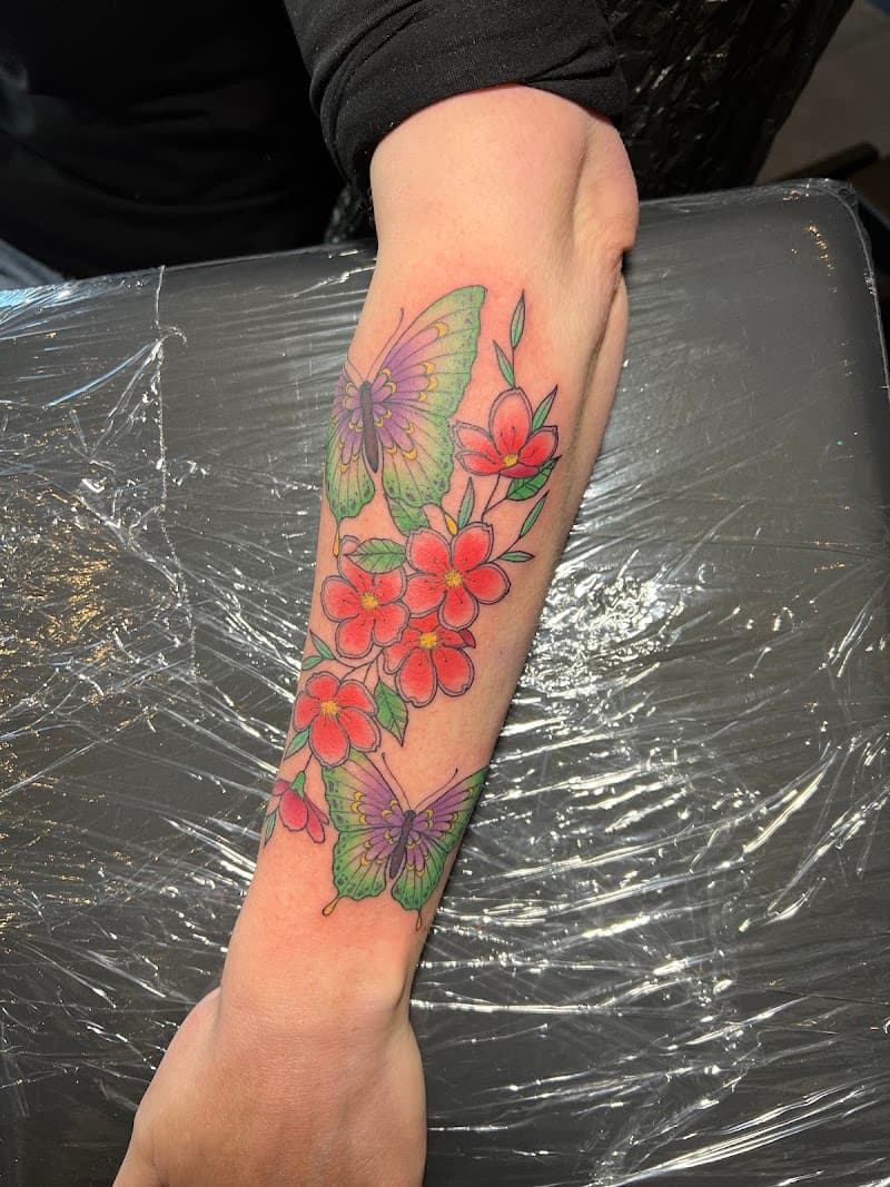 Kleurrijke vlinders en bloemen op onderarm.