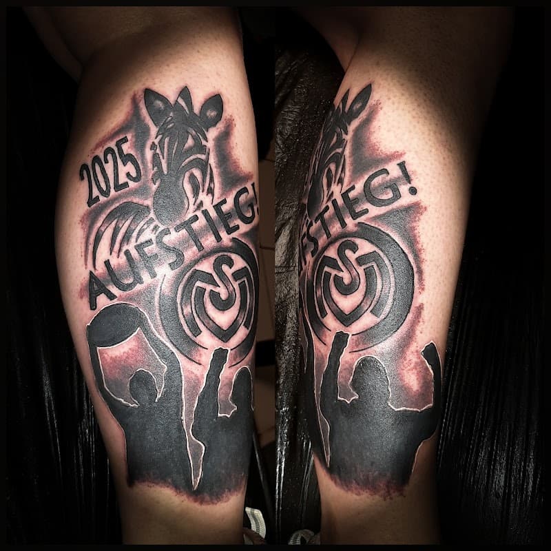Zwart-wit tattoo op onderbeen: zebra, '2025 AUFSTIEG!', MSV logo en fans.