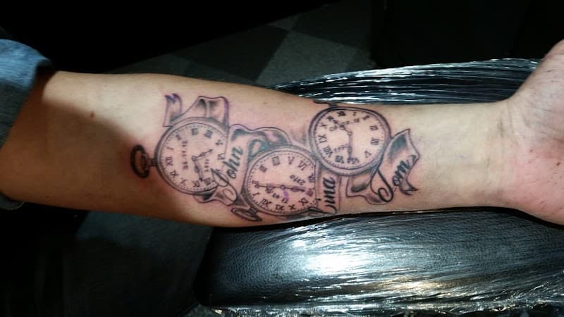 Drie zakhorloges met namen John, Tom en een derde op een lint, op de onderarm.