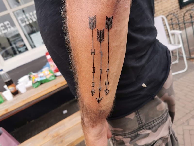 Drie minimalistische pijlen met letters op de onderarm.
