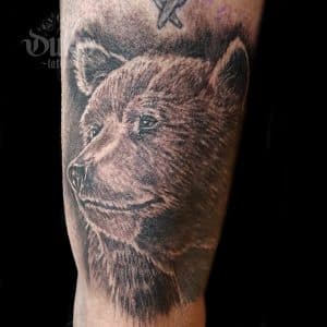 Realistische berenkop tattoo in zwart-wit op het onderbeen.