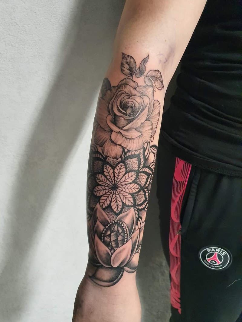 Zwart-grijze half-sleeve met een roos, mandala en lotusbloem op de onderarm.