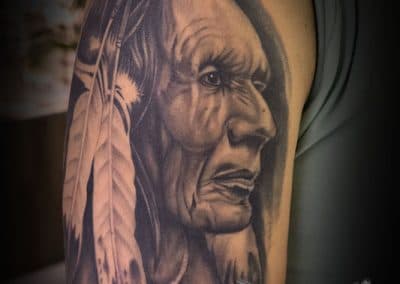 Realistisch portret van een Indiaans opperhoofd met veren op de bovenarm.