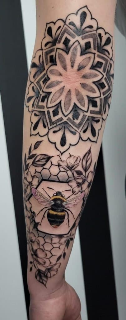 Mandala, realistische hommel en bloemen op onderarm.