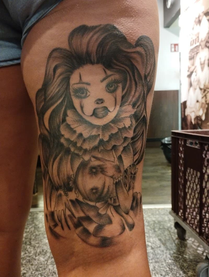 Zwart-wit Chicano tattoo van een vrouwelijke clown op het bovenbeen.