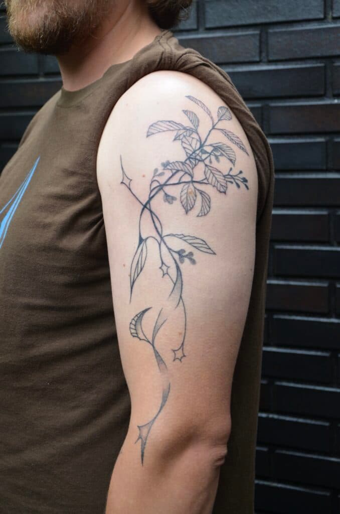 Fineline tak met bladeren, bessen en abstracte lijnen op bovenarm.