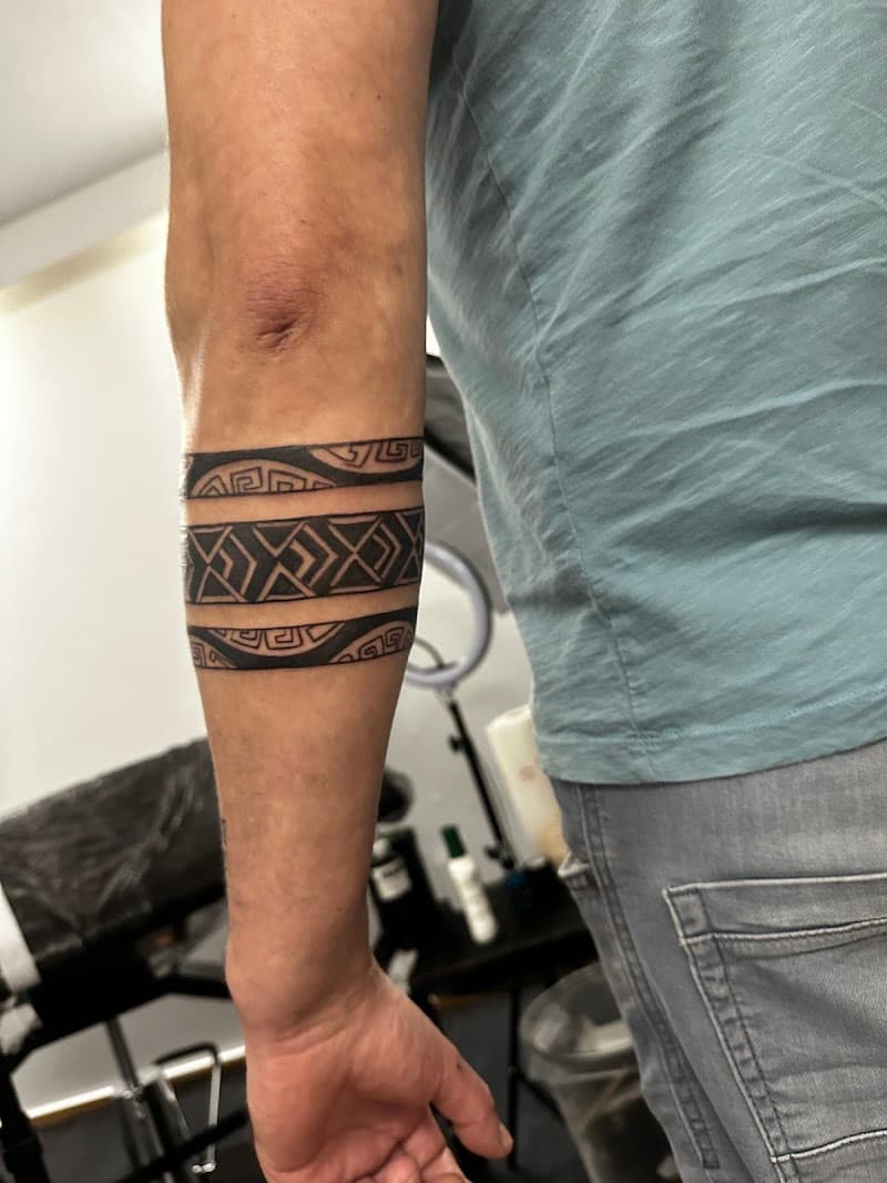 Zwart-wit tribal armband tattoo op onderarm met geometrische patronen.