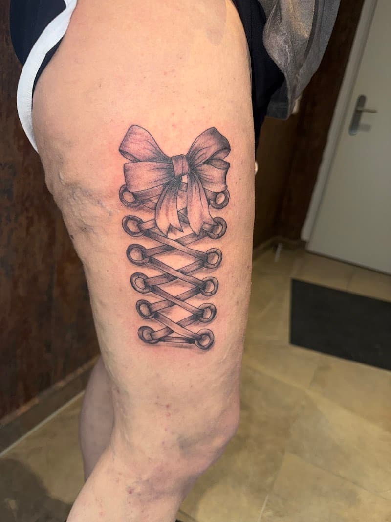 Realistische korsetvetersluiting met strik op bovenbeen.