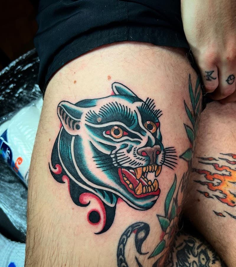 Traditionele panterkop tattoo op bovenbeen.
